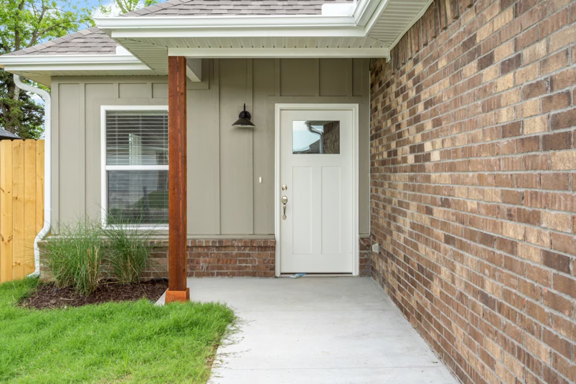 Covered front entry with a craftsman door and brick facade